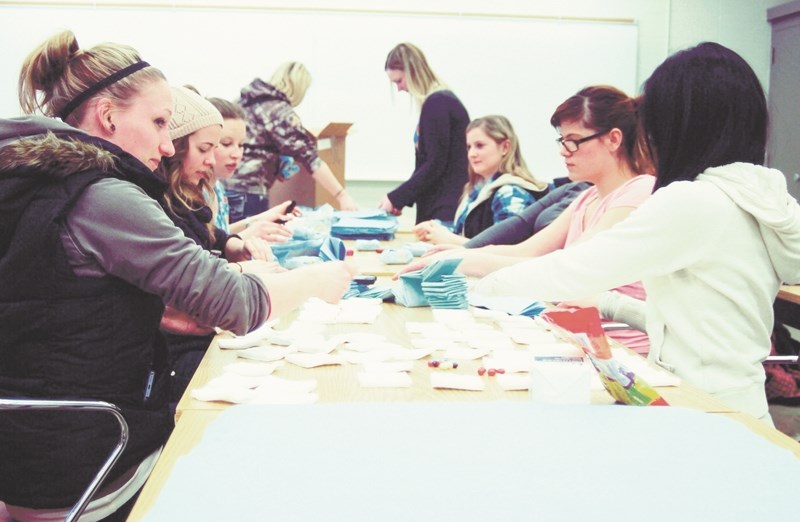 Students from Olds College&#8217;s animal health technologist and veterinary medical receptionist programs fold drape packs on March 31 in the Animal Sciences building. The