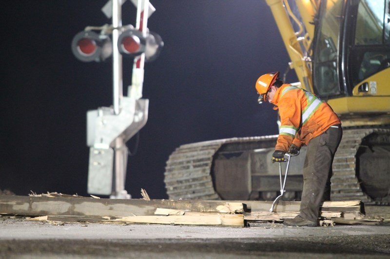 A Canadian Pacific Railway worker helps move pieces of railway track pulled out of the rail crossing on 57 Avenue south of town during the early morning hours of May 21.