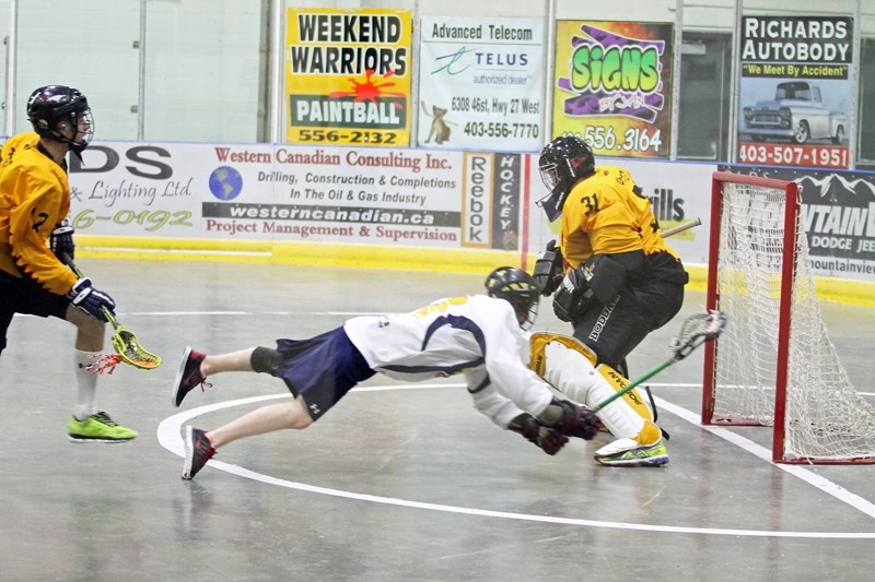 Olds junior B Stingers goaltender Kiefer Olsen blocks a shot from diving Medicine Hat Sun Devils player Tanner Dynes during a meeting of the two teams in Olds on June 22. The 