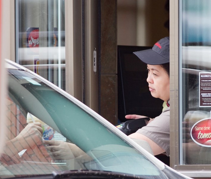 A former Temporary Foreign Worker program participant hands a customer a beverge through the Tim Hortons drive-thru window at the 46 Street location in Olds. The worker is