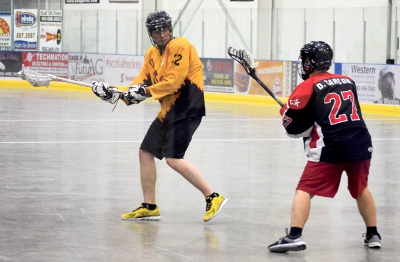 From left, Lucas Howard of the Olds Stingers is guarded by Derek Tarcon of the Crowsnest Pass Ravens during the Rocky Mountain Lacrosse League&#8217;s Junior B Tier III gold