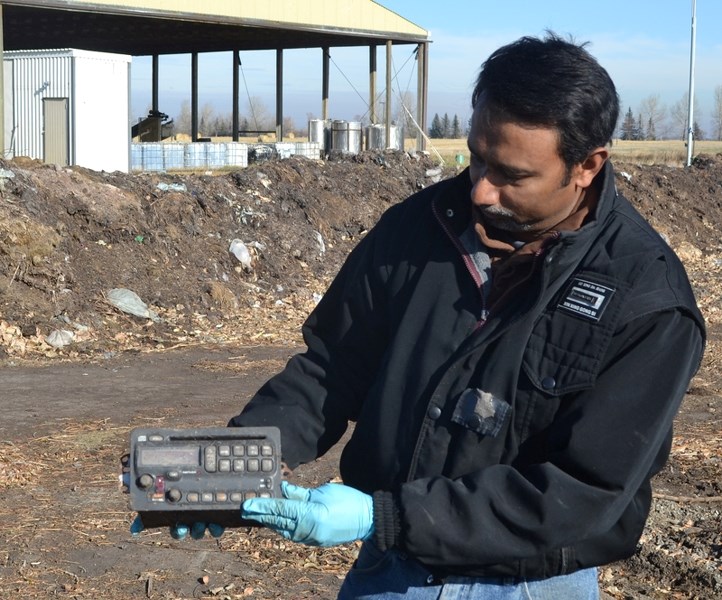 Olds College compost technician Nalaka Ileperuma says people have to do a better job of sorting their compost from their garbage. Here, he holds up a car stereo he found.