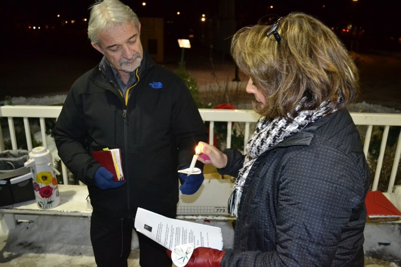 Olds and District Hospice Society vice-president Kathy Kemmere (right) lights a candle held by St. Paul&#8217;s Lutheran Church pastor John Lentz.