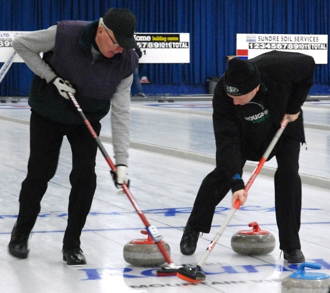 Lead Dennis Remillard, left, and second Morley Kjargaard of Olds sweep home a rock during the annual men&#8217;s bonspiel in Sundre on Saturday, Dec. 5. This weekend, the