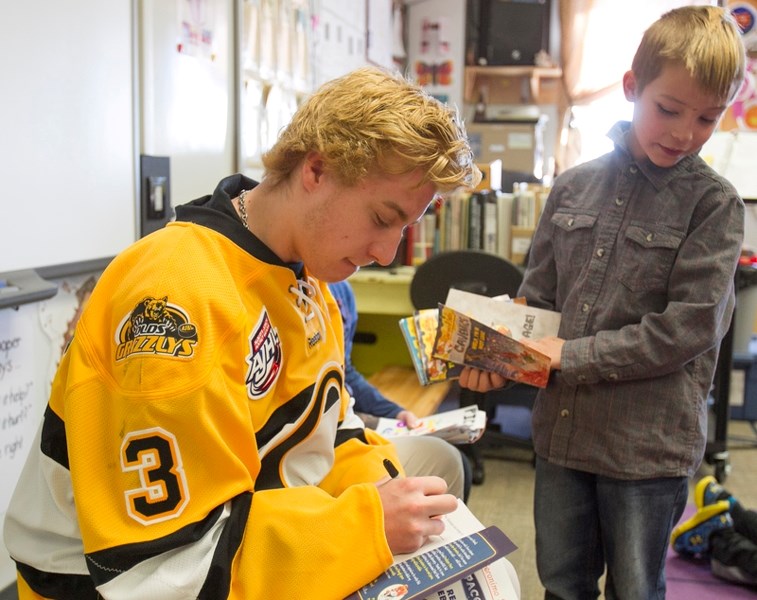 Olds Grizzlys player Austin Pickford signs a book for Olds Elementary School Grade 3 student Kye Delaney during the Grizzlys&#8217; visit to the school on March 8.