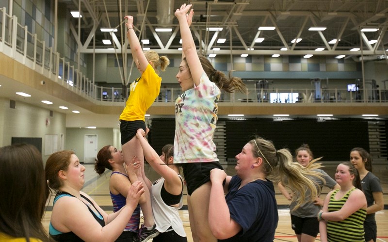 Grade 11 students Statia Powell, left, and Anteia Organ are hoisted in the air during an Olds High School girls rugby line out drill.