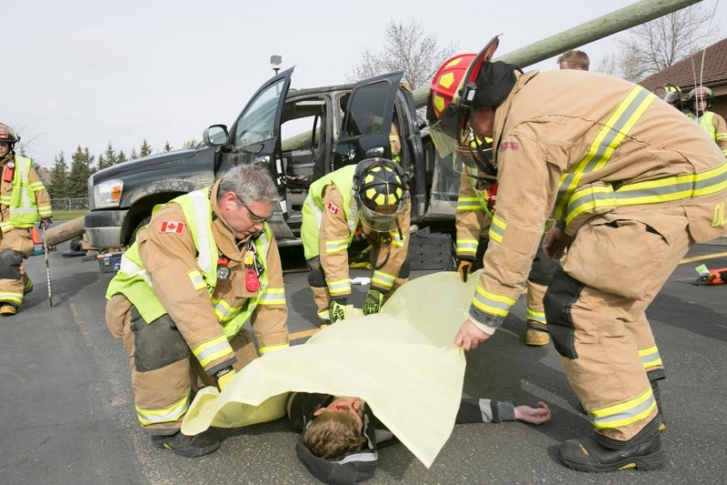 Olds firefighters place a sheet over Grade 12 student Keaton Miller, who played a deceased youth in the simulation.