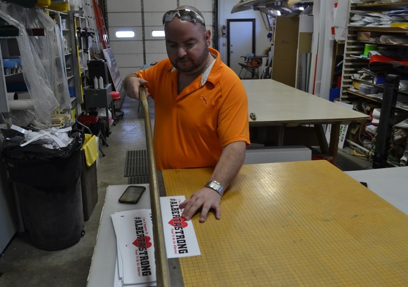 Eagle signs owner Robb Lussier of Olds trims the last of a batch of decals being sold to raise money for people affected by the wildfires in the Fort McMurray region.