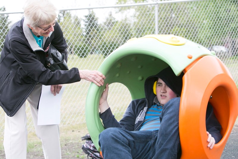 Inga Owens spins grandson and past student Kevin Owens in a piece of playground equipment.