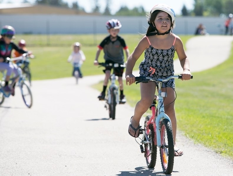 Olds Elementary School student Rhiannon DeLuca rides around a track behind the school during the Tour De Olds.