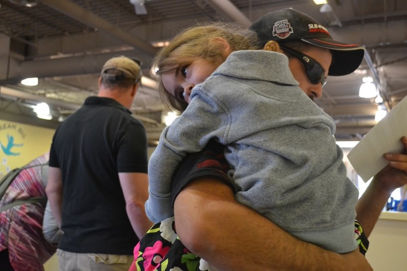 Elizabeth Bilodeau, 4, takes a rest on her dad Shane&#8217;s shoulder as she gets registered during the grand opening of the Olds Gymnastics Club.