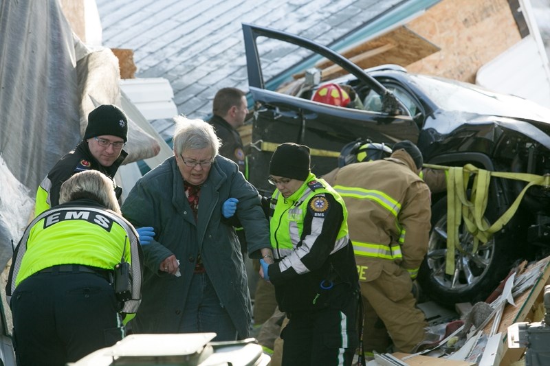 SHAKEN UP &#8211; EMS workers help an occupant of a vehicle away from the scene of an accident Friday, Feb. 3 in which the vehicle slammed into a garage and hit two homes.