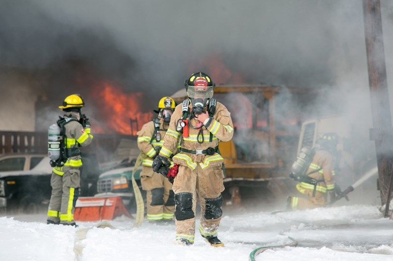 BIG BLAZE &#8211; A firefighter gets a break while others behind him keep up the battle after a major fire destroyed an old shop north of Olds containing about 80 cars and