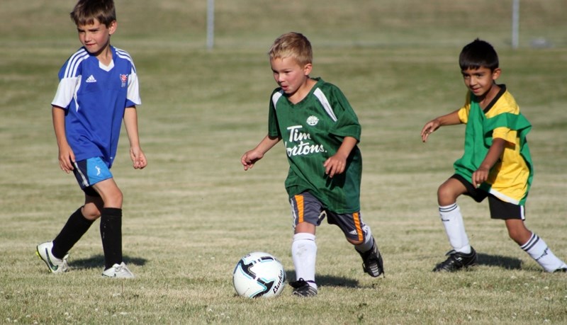 Micah Ellingsgaard, left, Luke Maas, centre, and Aidan Rajapaksa, right, rally during a mini game July 5 at Kick Off Soccer, Olds&#8217; first summer soccer skills camp. The