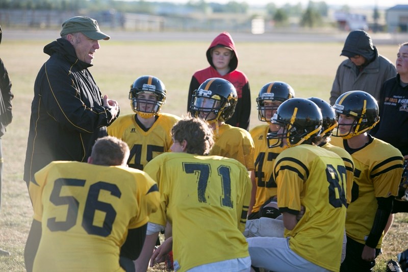 Coach George Grant speaks with the Spartans football team during practice.