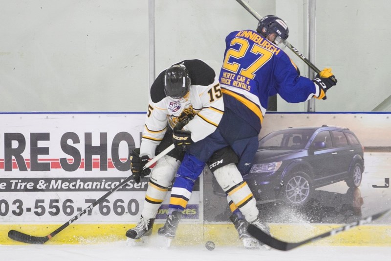 Olds Grizzlys forward Jack Berger fights for the puck with Fort McMurray Oil Barons defenceman Gunner Kinniburgh along the boards during a game at the Olds Sportsplex on Oct. 