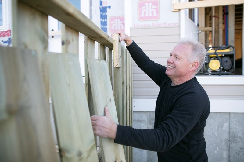 Wayne Sollid works on a fence at the back of the duplex.