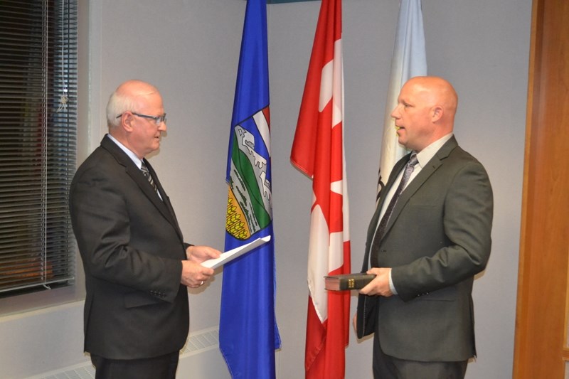 Chief administrative officer Michael Merritt, left, swears in mayor Michael Muzychka during Olds council&#8217;s organizational meeting Oct. 23.