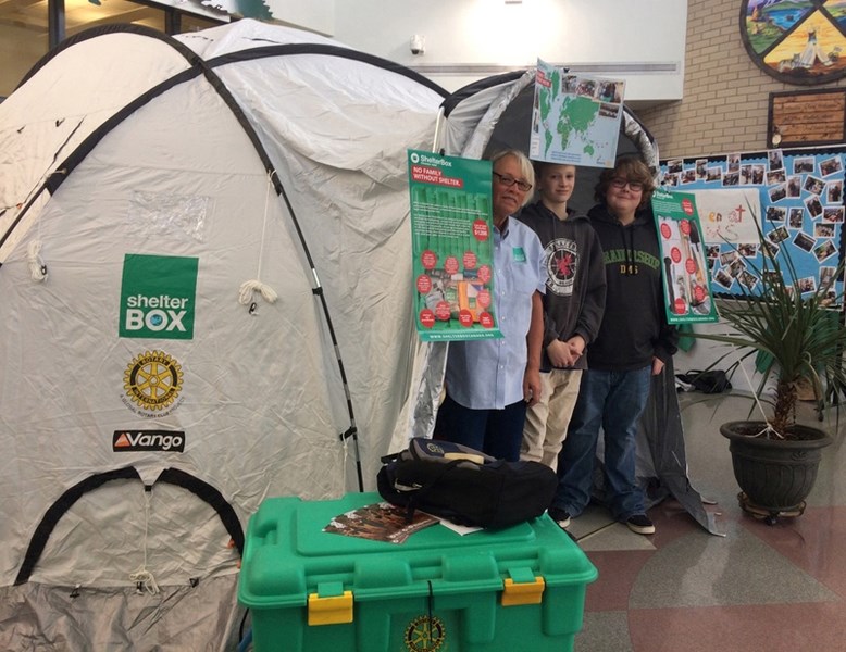 From left, Wynne Bjorgan of The Rotary Club of Red Deer East along with students Liam Carrick and Mason Rompain peek out of a ShelterBox tent they erected at Ecole Deer