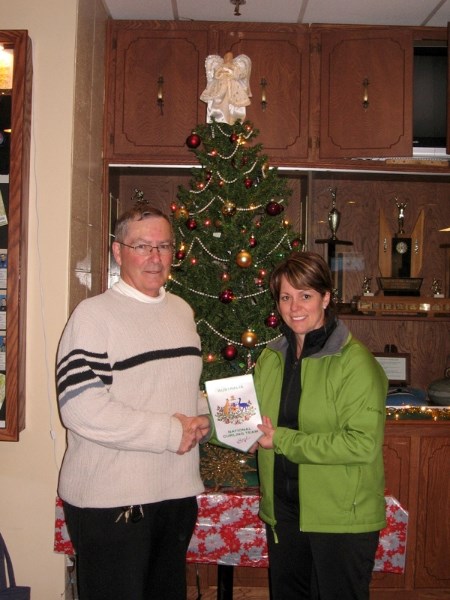 Olds Curling Club member Dale Holmes accepts an Australian National Curling Team banner to commemorate Australian skip Kim Forge&#8217;s participation in the Ironman Bonspiel.