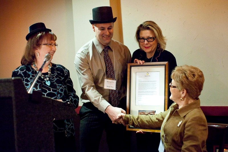 Donna Erdman, left, of the Olds Historical Society, Mayor Judy Dahl, second from right, and Donna Coonfer, right, of the Olds Historical Society present a Heritage Properties 