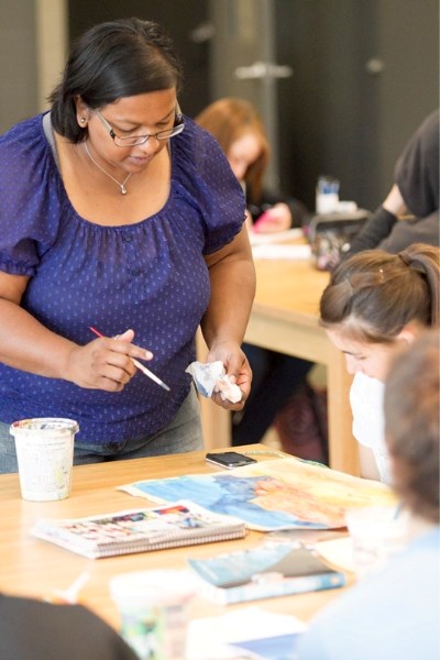 Olds High School teacher Renu Mathew helps students with art projects in an Art 10 class at the school on May 10.