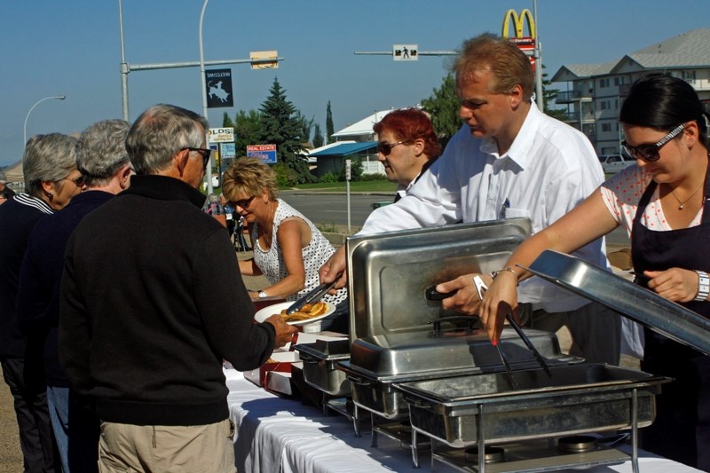 Rob Della Siega, owner of the Olds Sobeys supermarket, one of the sponsors of a community pancake breakfast in support of flood relief in southern Alberta, serves sausages on 