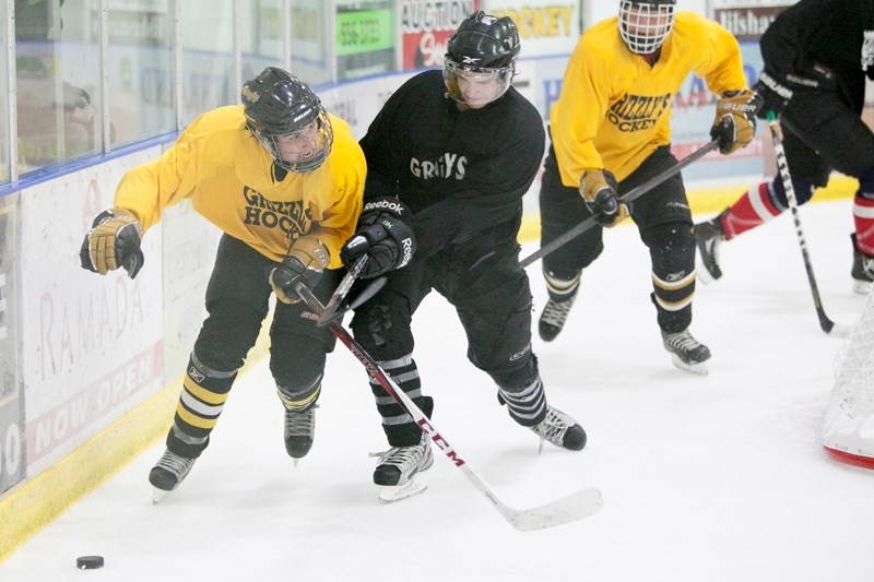 Olds Grizzlys prospect Ryan Klinck, left, fights for the puck during the annual Black and Gold game at the Olds Sports Complex on Aug. 23.