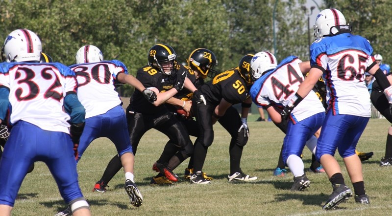 Centre Klay Quilley snaps the football to quarterback Connor Jorgensen (No. 23) during the Olds High School Spartans&#8217; football game on Sept. 14 at Normie Kwong Park.