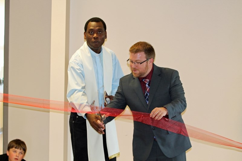 Father Maurice Okolie and Holy Trinity Catholic School principal Mike Cellini cut a ribbon to open a new portable complex at the school on Sept. 20.