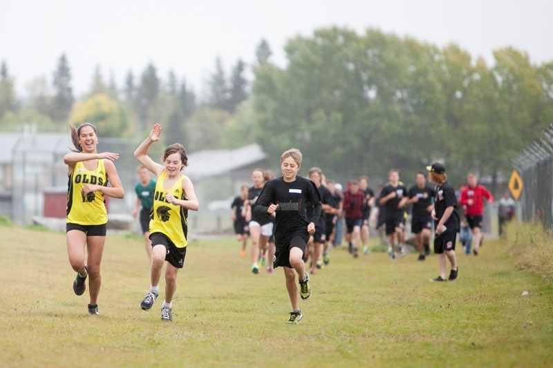 Olds High School students Janelle Graham, left, and Leif Aitken high-five each other near the beginning of their race during a cross-country race hosted by Sundre High School 