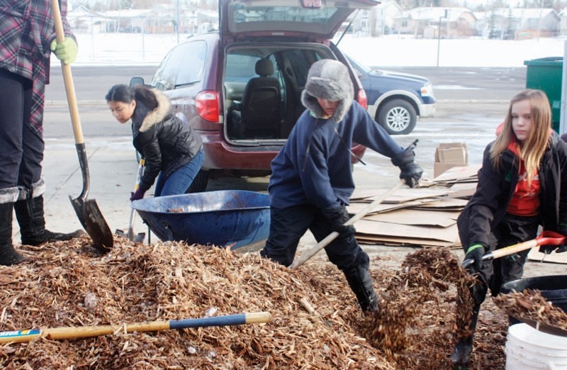 Jamie Nate, Conner Dixon and Sierra Bjarnason shovel mulch on Oct. 30 during a work bee held by creative gardening academy students at Ecole Deer Meadow School.