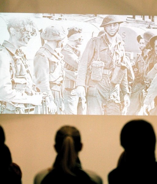 Students watch a video and slideshow of footage and photographs documenting Canada&#8217;s military engagements over the past century during a Remembrance Day ceremony at