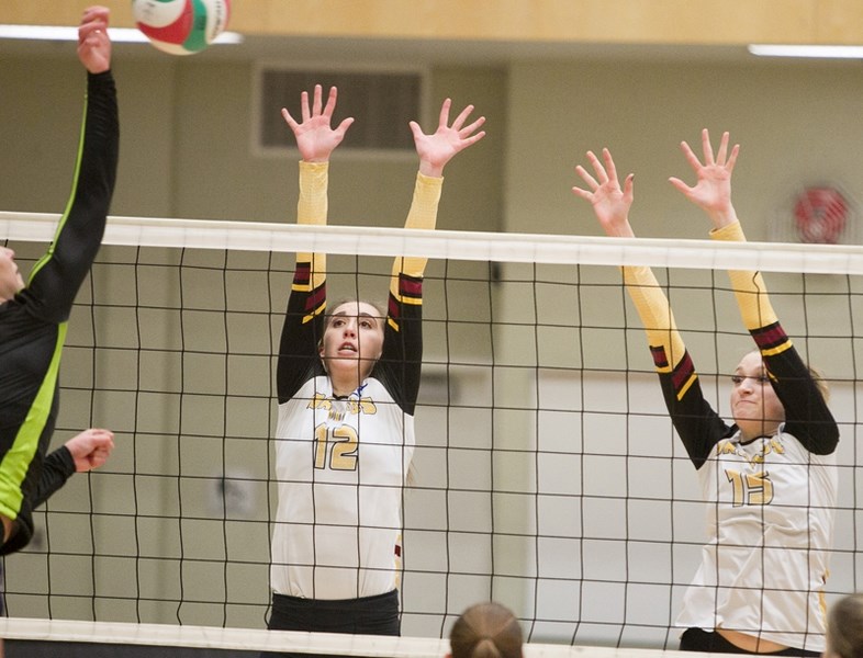 Olds College Broncos volleyball players Karley Dieken, left, and Bianca Pollock attempt to block a shot during a game against the Red Deer Queens at the Ralph Klein Centre on 