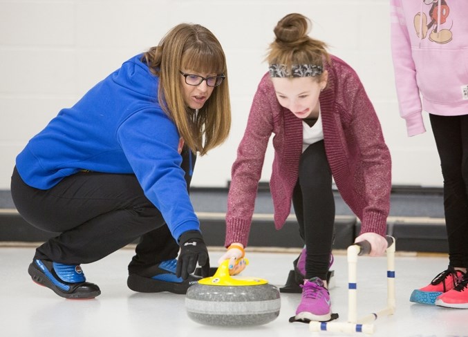 Former national curling champ Heather Nedohin works with Sarah Hoppins of Deer Meadow School at the Olds Curling Club.