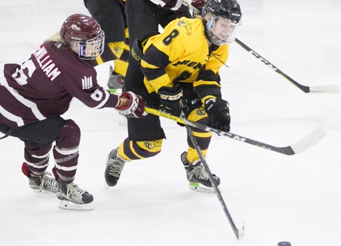 Olds College Broncos hockey player Faith Volk battles for the puck during the Broncos&#8217; game against the Grant MacEwan University Griffins at the Olds Sportsplex on