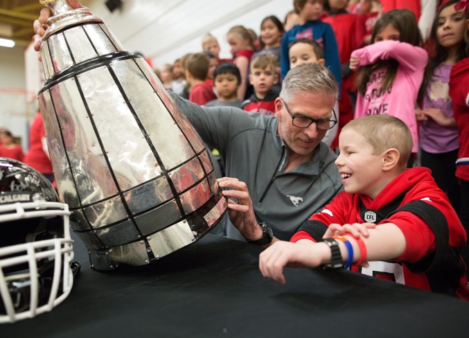 Stampeders alumnus Jay McNeil shows the Grey Cup to Thompson.