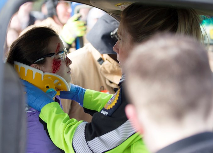 An EMS worker assists Emma Legris during the mock collision simulation.