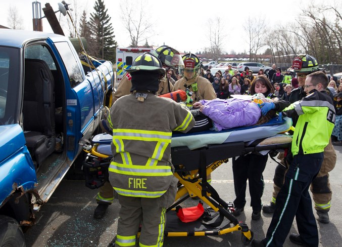  Olds firefighters and EMS workers remove Emma Legris from a vehicle during a mock collision staged May 1 at the Church of Jesus Christ of Latter-day Saints. Noel West/MVP Staff