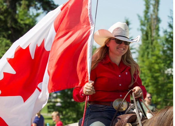 A rider carries a Canadian flag during the parade.