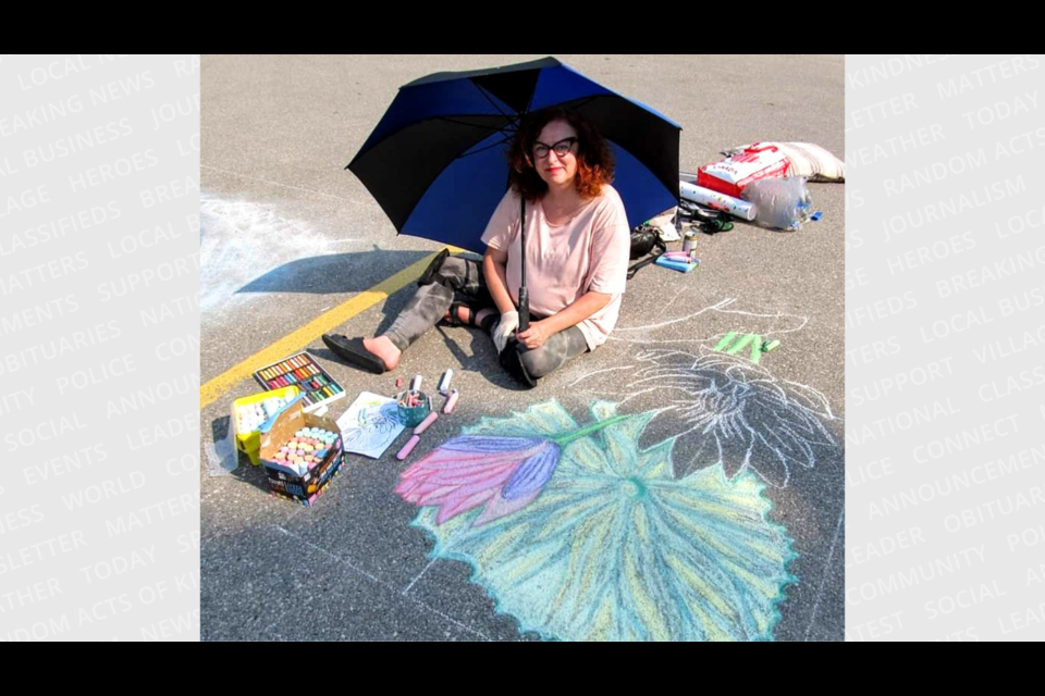 Kim Egan shades herself from the sun while working on her art.