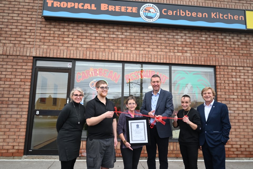 Newmarket dignitaries cut a ribbon outside of Tropical Breeze Caribbean Kitchen. From left, Councillor Grave Simon, Ryan Noble, owner Bonnie Powell, Mayor John Taylor, Linds Basciano, Deputy Mayor Tom Vegh.