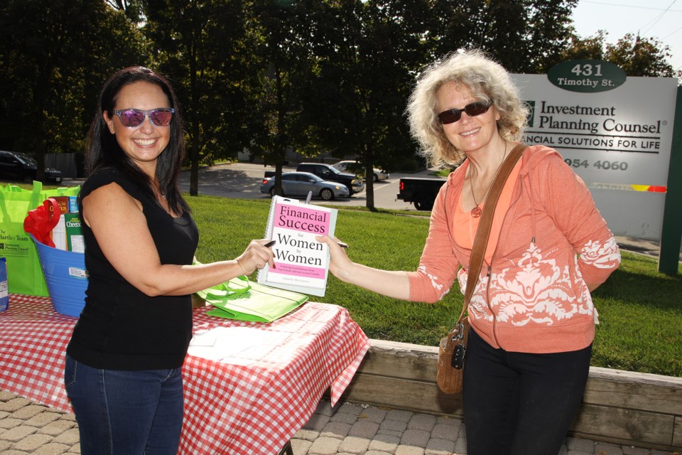 Donna Kosark (right) receives a copy of Andrea Bartley's book for her donation to Newmarket Food Pantry at Saturday's fundraiser.  Greg King for NewmarketToday