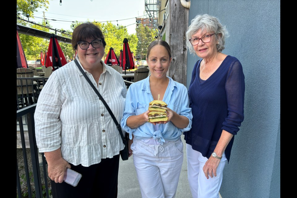 Anne Marie Devine, communications for CFUW Aurora/Newmarket (left), Samantha Buckley, co-owner of Ground Burger Bar, and Mary Weber, event organizer for CFUW, present the Grad Burger.