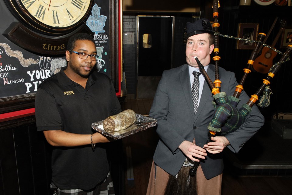 Connor Elliott pipes in the haggis held by Newmarket Fionn MacCool's manager Richard Harry on Robbie Burns Day last night.  Greg King for NewmarketToday