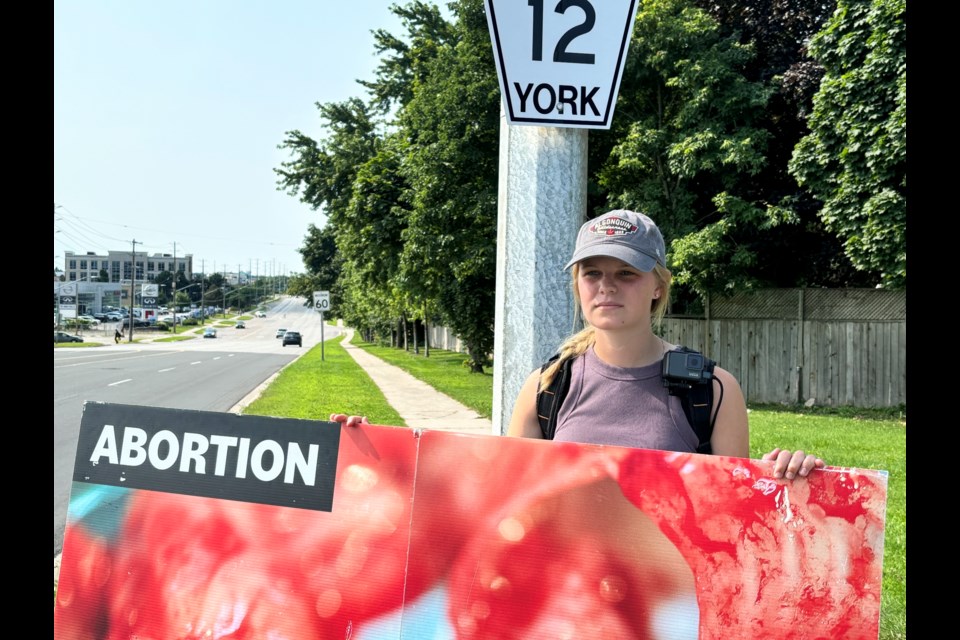 Naomi Meestra, team leader, waved a sign with a graphic anti-abortion images on Leslie Street at Davis Drive in Newmarket July 23.