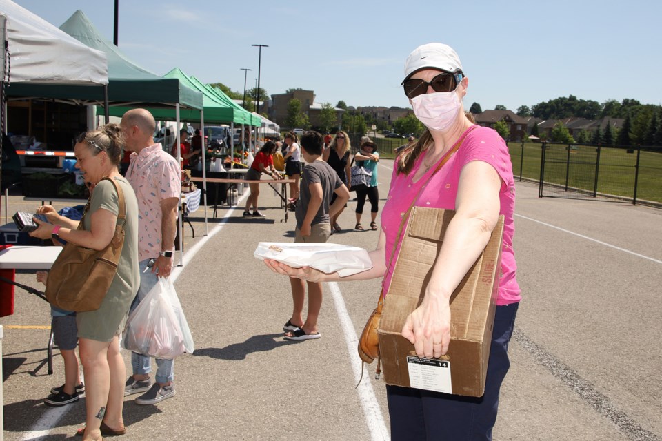 You can visit the Newmarket Farmers' Market in person at the Magna Centre parking lot. Robin Knighton picks up an apple strudel and a Coopers Farm share box yesterday.  Greg King for NewmarketToday