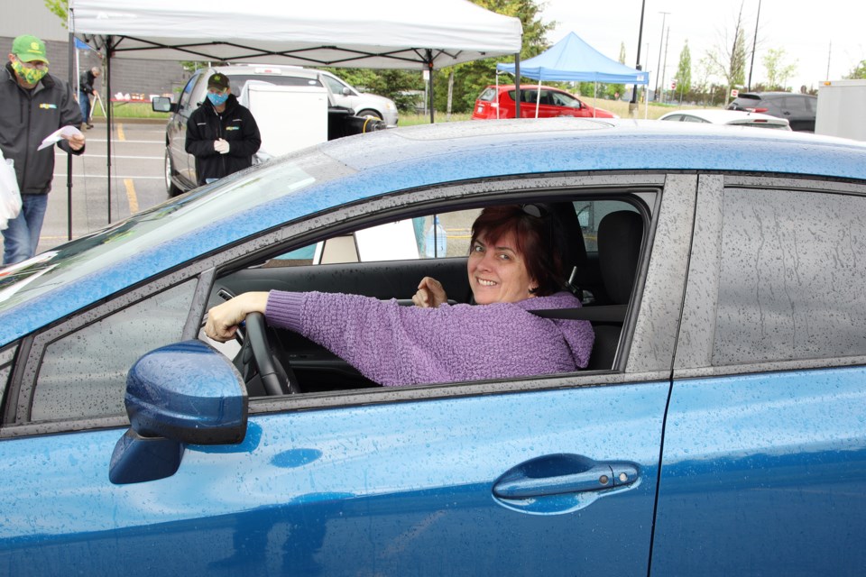 Jennifer Tucker is picking up her order from Farm Girls Kitchen on opening day of the Newmarket Farmers Market May 30.  Greg King for NewmarketToday