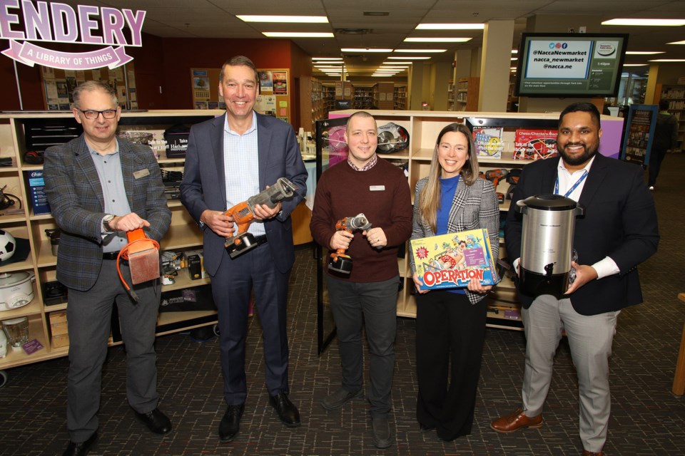 Newmarket Public Library CEO Todd Kyle, Newmarket Mayor John Taylor (note saw for cutting red tape), library staff Biagio Rachiele, manager of York Region's Sustainable Waste Management Lindsay Milne, and Sustainable Waste Management staff Myron McLelland mark the grand opening of the Lendery today at Newmarket Public Library.  Greg King for NewmarketToday