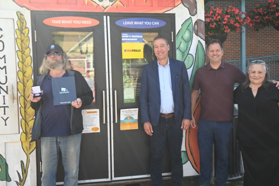 Volunteer Duke Deger receives a new Town of Newmarket medal from Mayor John Taylor, alongside Newmarket Food Pantry executive director Adrian Brain and resource development co-ordinator Vesna Mitchell.